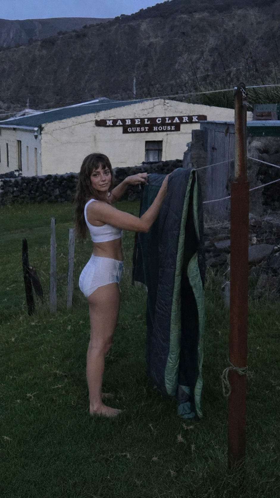 A confident traveler hanging laundry outside the Mabel Clark Guest House, embracing everyday life on the road
